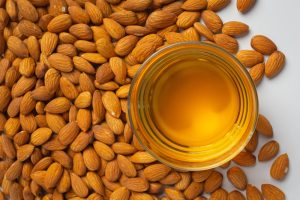 imagen de aceite de almendra en una mes con almendras alrededor