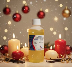 Envase de la fragancia vainilla al aceite con fondo navideño de velas añromáticas